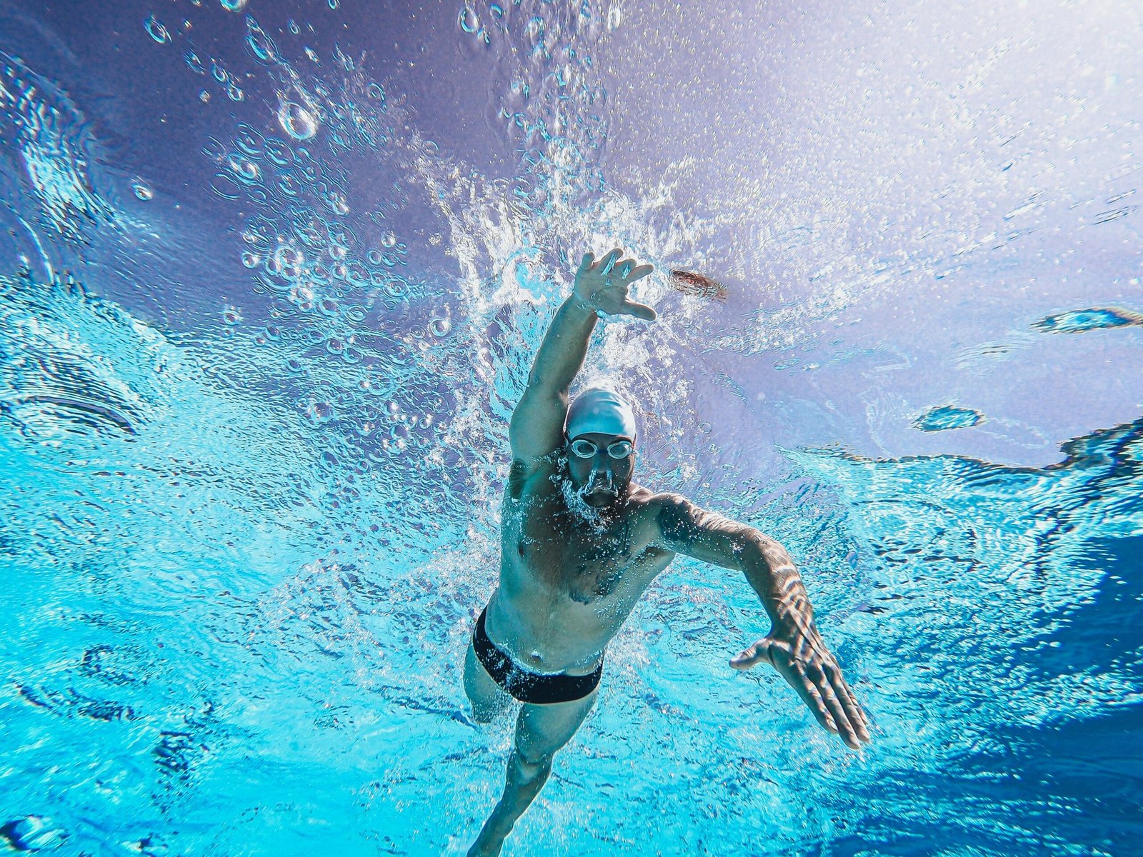 Dynamic shot of a male swimmer in action underwater, showcasing athletic skill and technique.
